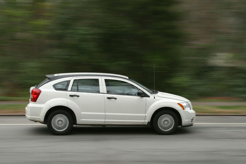 a white car with strong horsepower and torque is speeding on the road